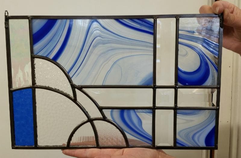 Hands holding a leaded glass panel in a beginning stained glass class