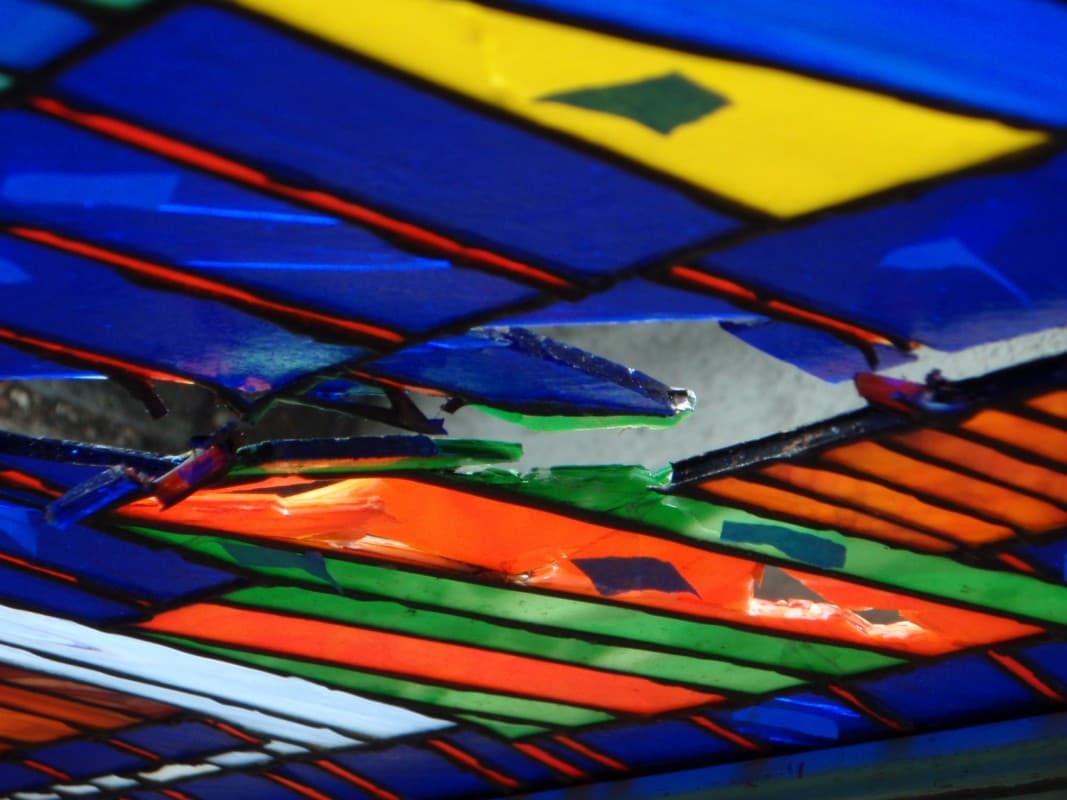 Damaged stained glass cityscape with broken pieces marked in blue tape